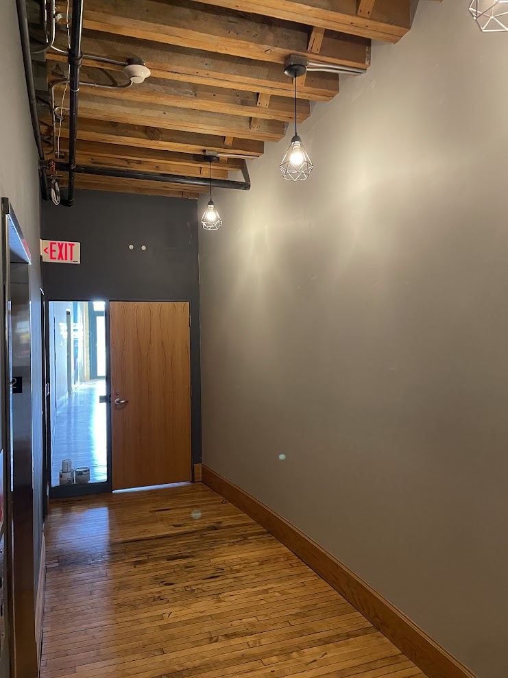 Suite 200 entry with exposed timber ceiling, pendant lighting and the door through to the elevator lobby.