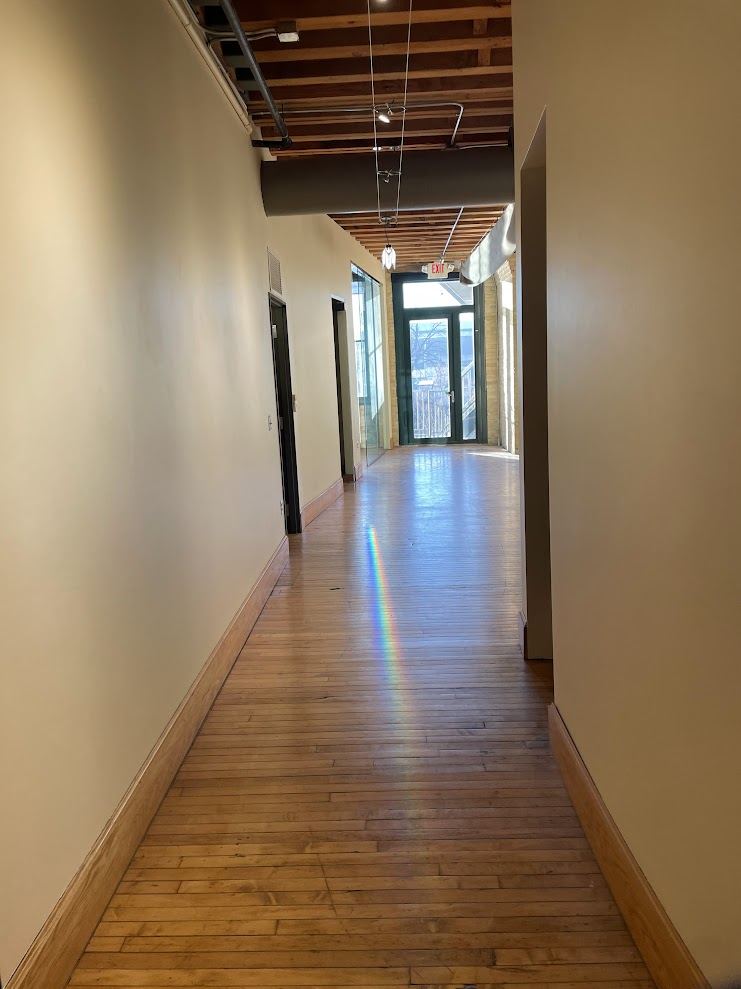 Corridor in Suite 250 with original maple flooring running toward the river-facing doors.