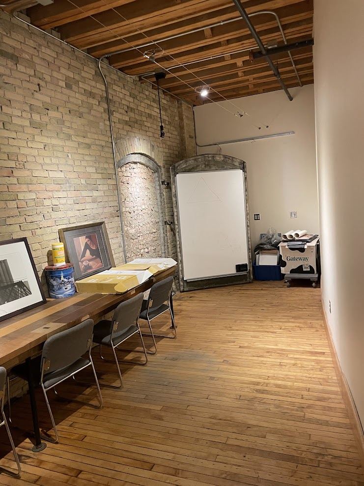 Meeting room in Suite 250 with a long table against the brick wall and an original arched opening exposed in the masonry.
