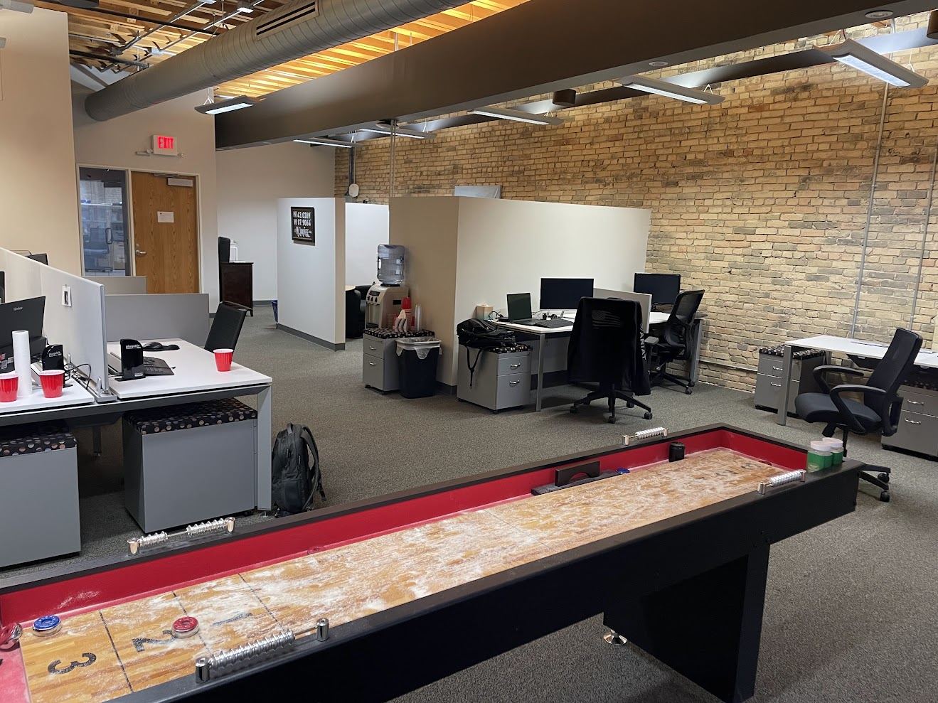 Wide view of Suite 400's open floor with brick wall, timber ceiling and daylight from the Water Street windows.