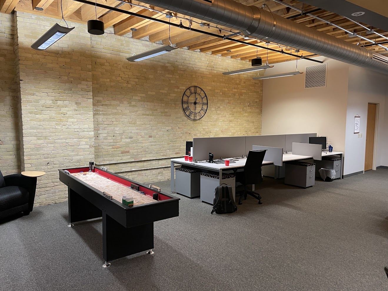 Open work area in Suite 400 with a long Cream City brick wall, timber ceiling and workstations.
